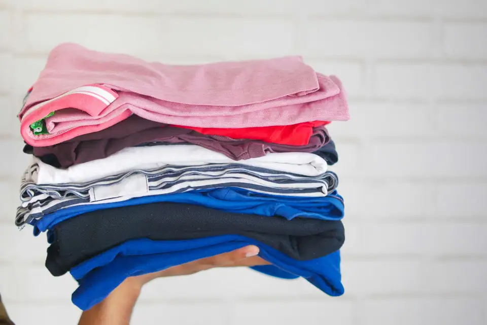 A stack of folded shirts in red, white, blue and pink