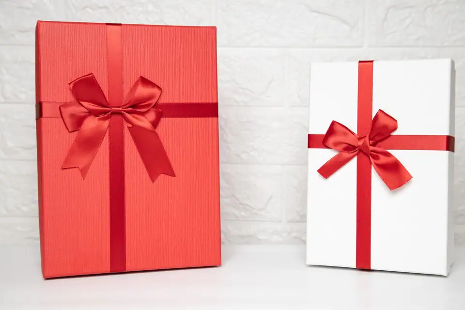 A red gift box and a white gift box tied with red ribbon