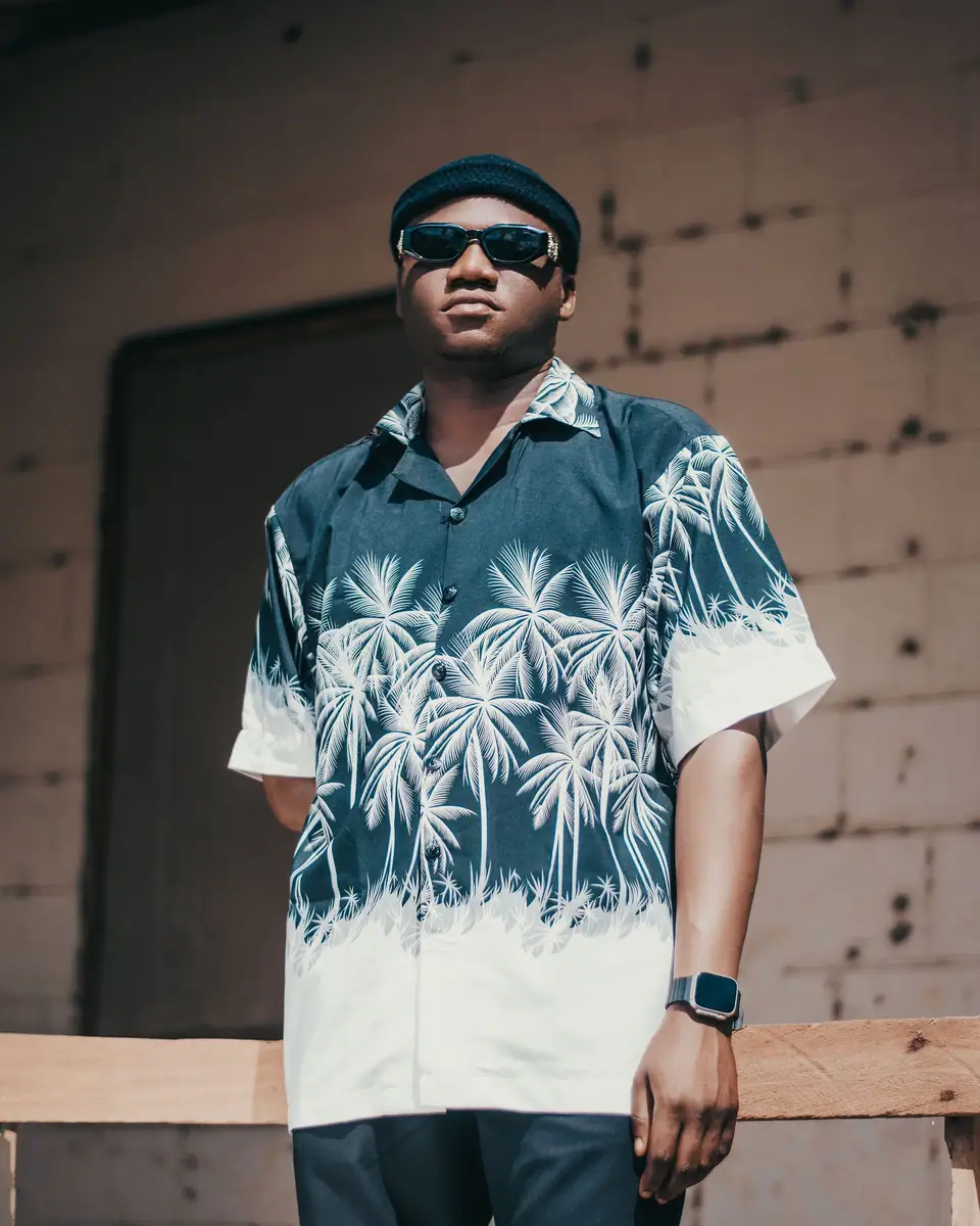 A man in sunglasses wearing a navy and white palm print camp shirt